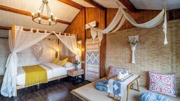 Quarto com cama, sofá, mesa pequena e rede suspensa.