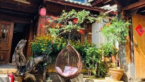 A traditional wooden building with a hanging chair and potted plants. - Lijiang Aduke Inn (Lijiang Ancient City Mufu Branch) (Lijiang)