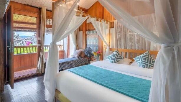 A bedroom with a bed, a wooden headboard, a window, and a door. - Lijiang Aduke Inn (Lijiang Ancient City Mufu Branch) (Lijiang)