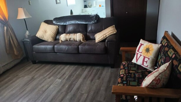A living room with a dark leather sofa, a wooden bench, and a patterned cushion. - This apartment is a 1 bedroom(s), 1 bathrooms, located in Pierre, SD. (Pierre)