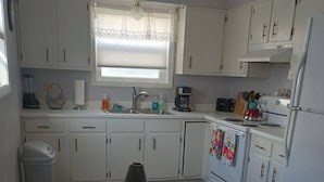 A kitchen with white cabinets, a sink, a stove, and a refrigerator. There is a dining table with chairs. - This apartment is a 1 bedroom(s), 1 bathrooms, located in Pierre, SD. (Pierre)