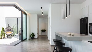 Eine moderne Küche mit integrierter Kochinsel, schwarzen Barhocker und einem schwarzen Kühlschrank.