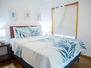 A bedroom with a bed, a nightstand, a lamp, and a window with curtains.