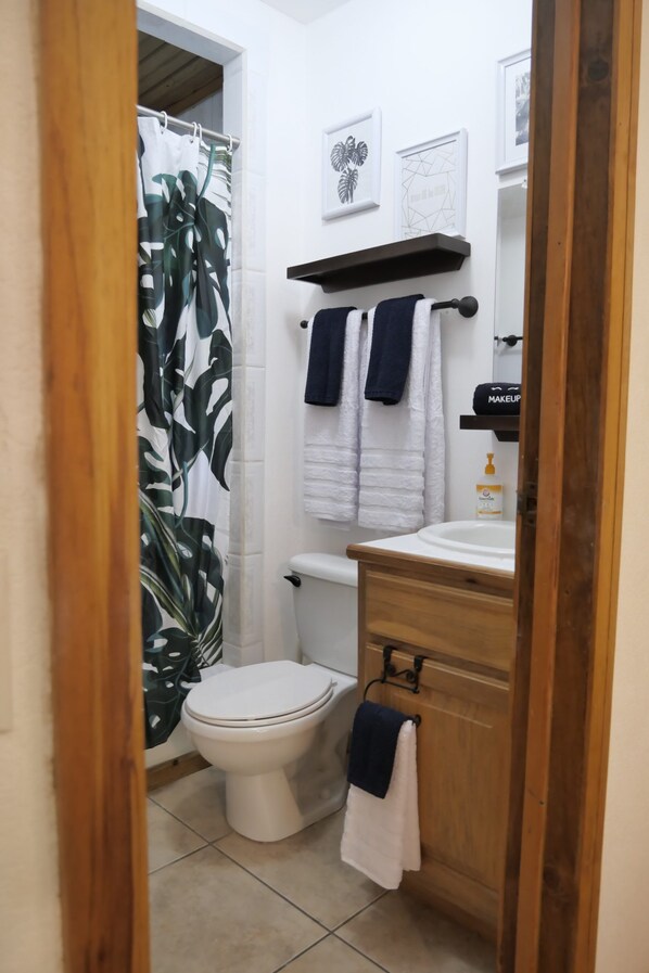 A bathroom with a toilet, a sink, a shower curtain, and a towel rack. - Casita de Nómadas - 2 Bedroom Beach House (Sandy Bay)