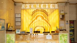A reception desk with a marble counter, framed certificates on the wall, and a sign indicating the name of the hotel. - Jinshengyuan Business Hotel (Yunfu)