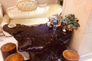 Una habitación con un sofá de cuero, una mesa de centro de madera singular y una pequeña planta.