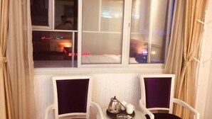 A hotel room with a bed, a window with curtains, two chairs, and a small table with a teapot and cups. - Jinshengyuan Business Hotel (Yunfu)