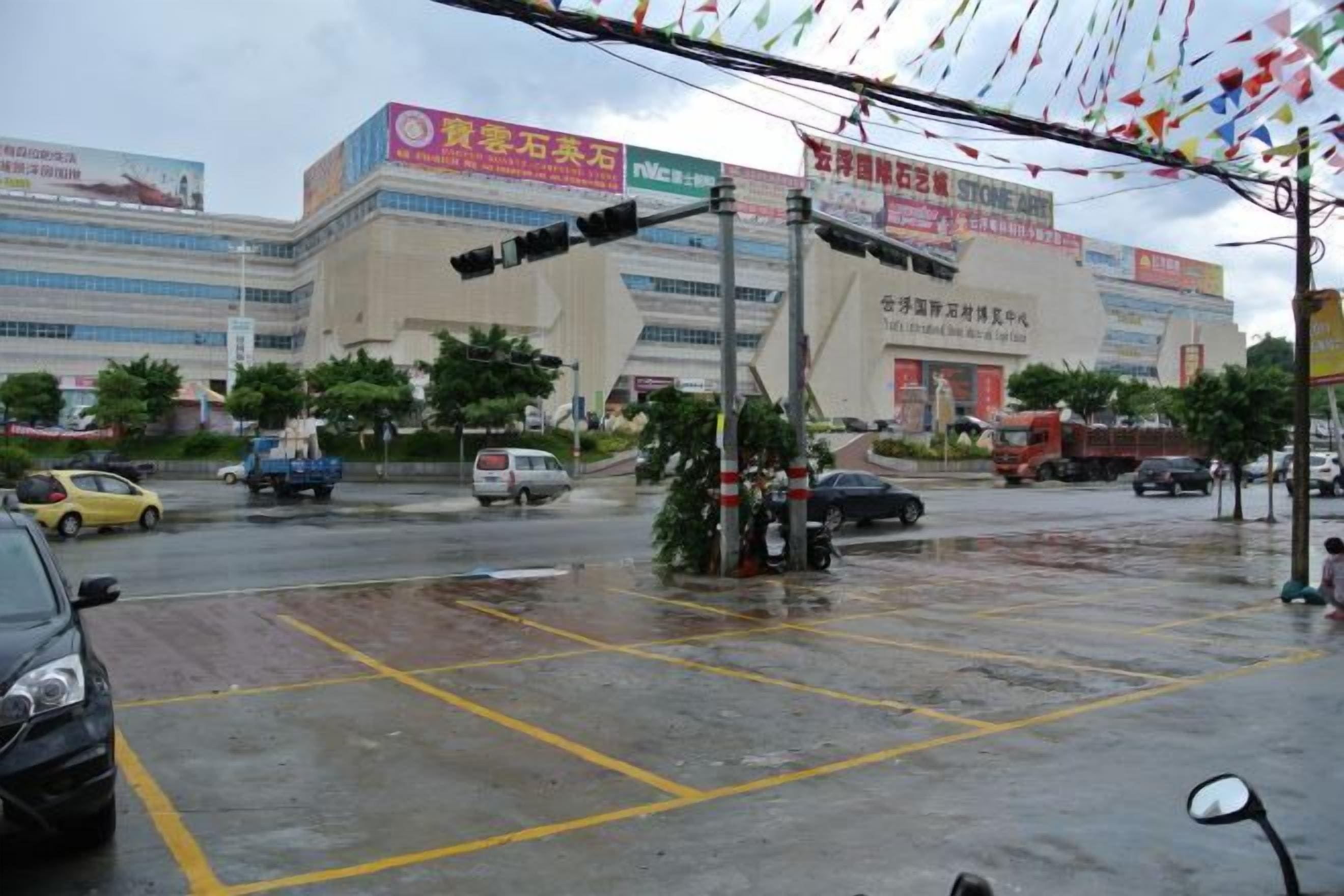 A wet intersection with traffic lights, a building with signage, and vehicles.