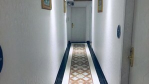 A hallway with patterned flooring, white walls, and doors at the end. - Jinshengyuan Business Hotel (Yunfu)