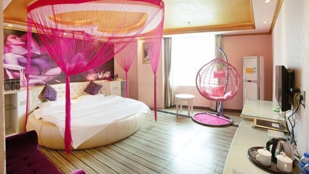 A bedroom with a canopy bed, a hanging chair, and a desk with a chair. - Jinshengyuan Business Hotel (Yunfu)