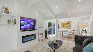 Un salon moderne doté d’un téléviseur à écran plat, d’une cheminée, d’un coin repas et d’un canapé.