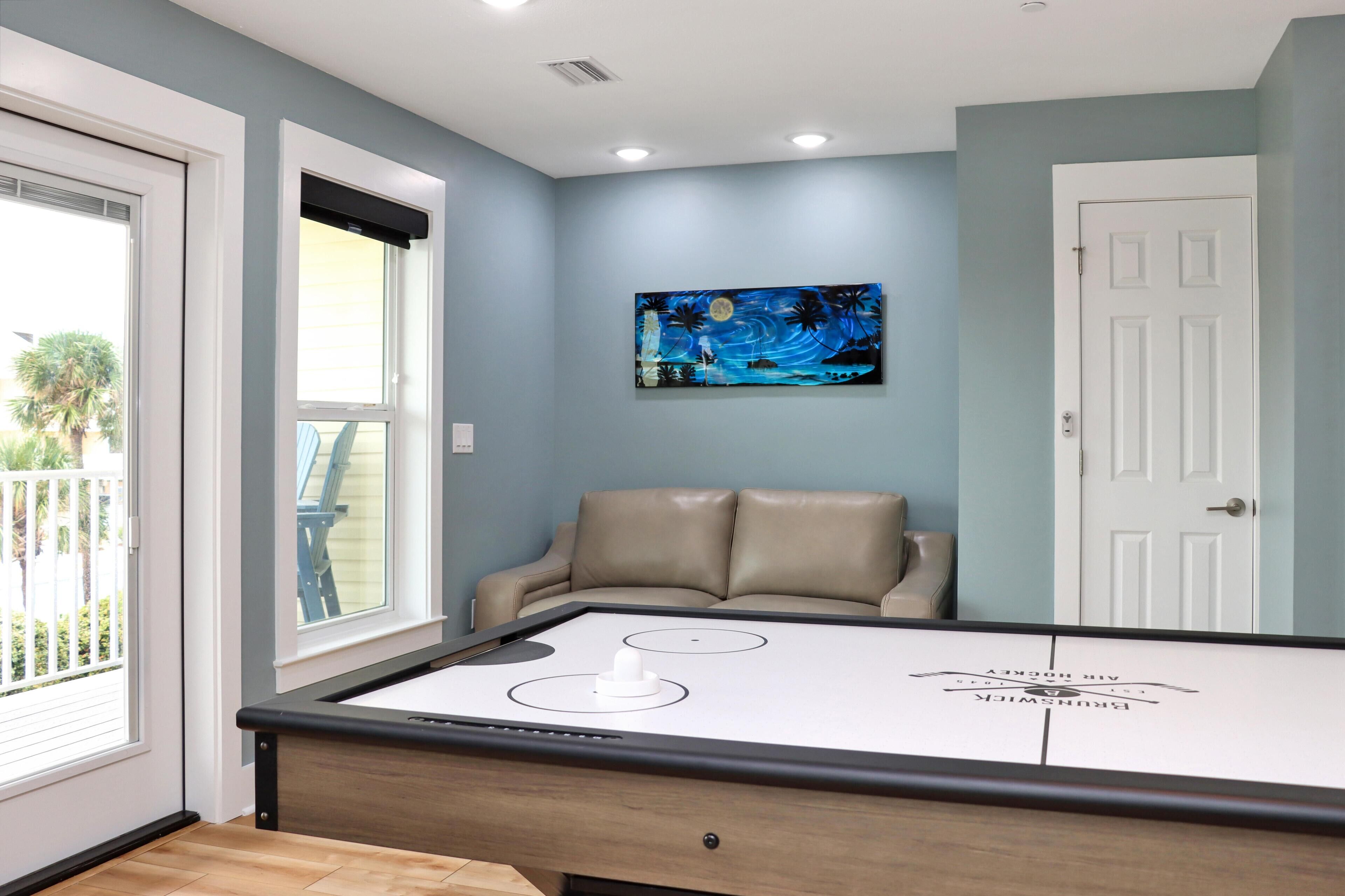 A pool table in a room with a light blue wall, a beige sofa, and a door.
