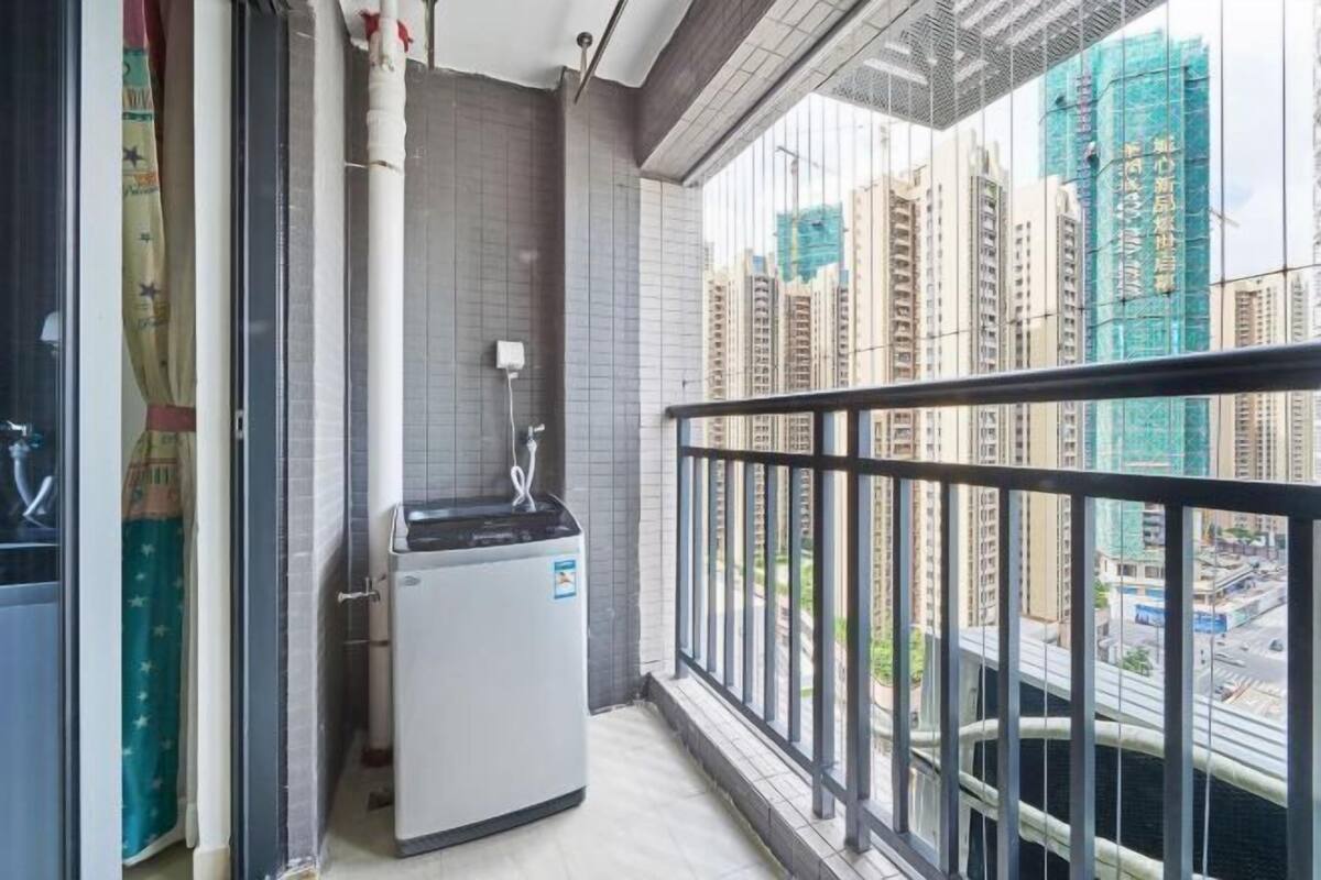 A balcony with a view of high-rise buildings and a small refrigerator.