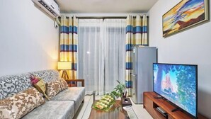 A living room with a sofa, TV, and a plant. - Shanghe Apartment (Shenzhen Science and Technology Park MixC World) (Shenzhen)