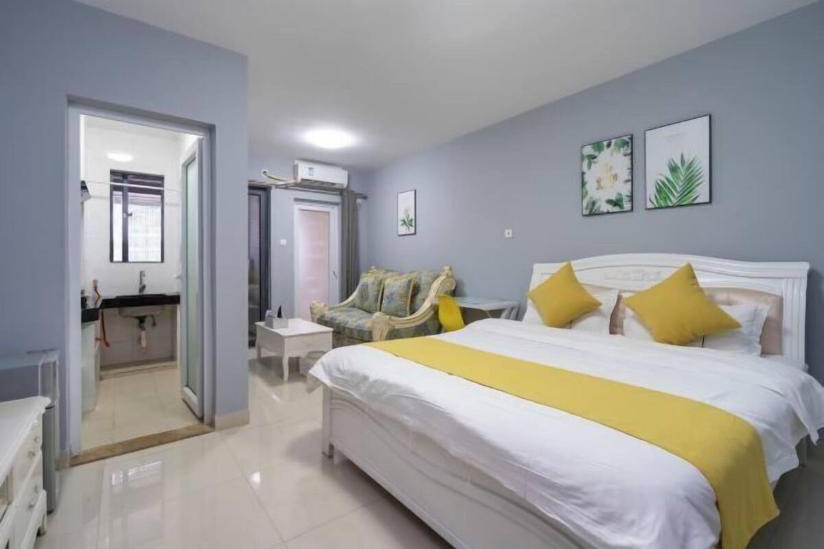 A hotel room with a large bed, a chair, a small table, and a mirror.