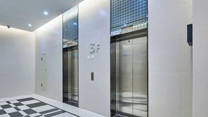 A modern elevator area with a checkered floor pattern, two elevators, and a wall-mounted sign indicating the floor level. - Shanghe Apartment (Shenzhen Science and Technology Park MixC World) (Shenzhen)