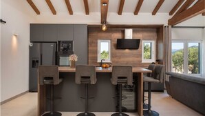 A modern kitchen with a bar area, built-in appliances, and a TV. - Villa Unika heated Pool, Jacuzzi, Sauna (Opanci)