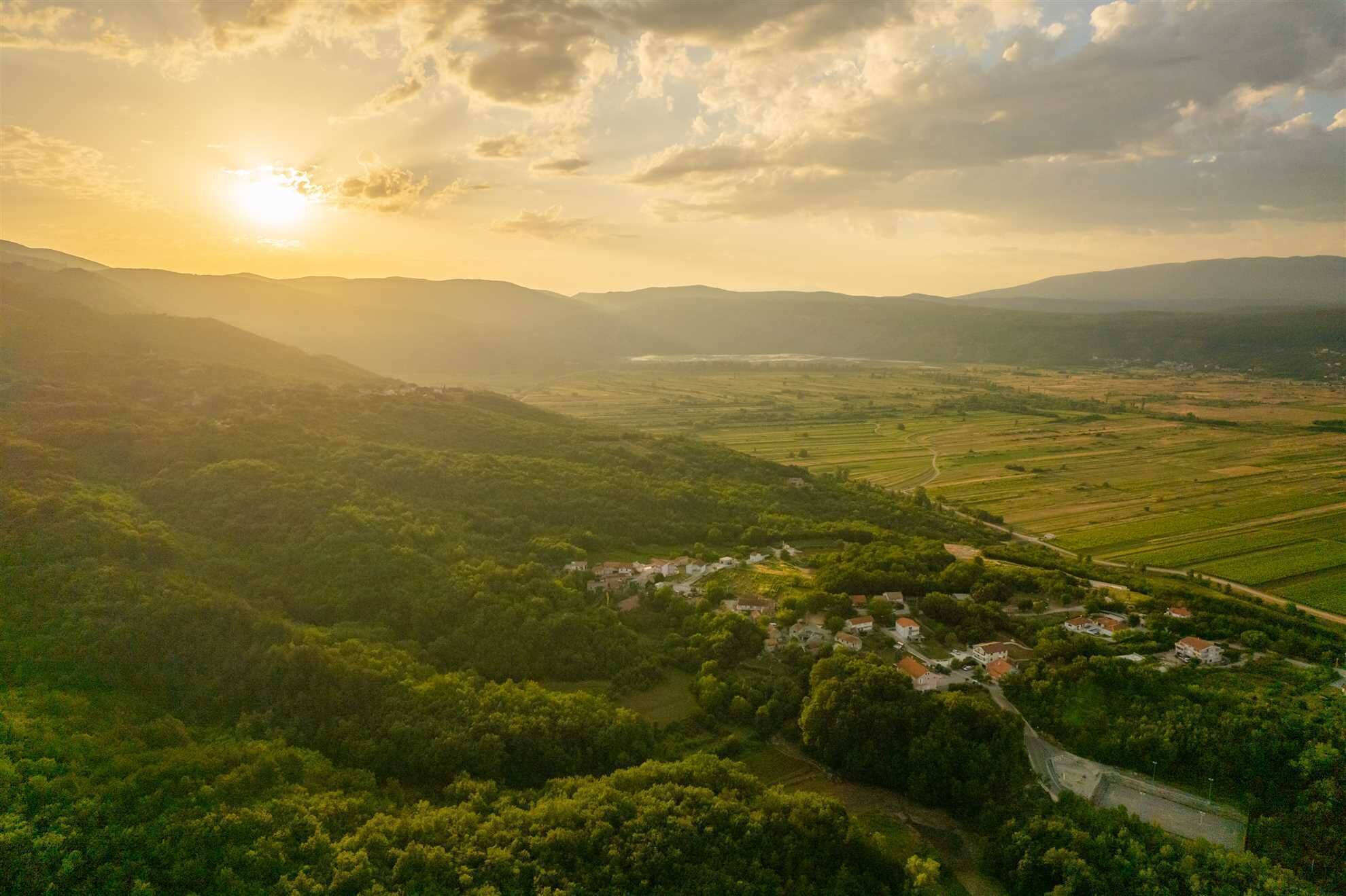 A rural landscape with a small village nestled among green fields and hills.