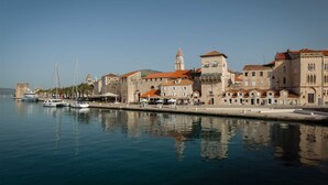 A waterfront with historic buildings, a clear sky, and boats docked.