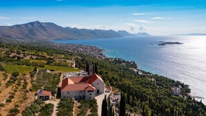 Une ville côtière qui se distingue par une église imposante dotée d’un clocher, entourée de vignobles et de forêts denses.