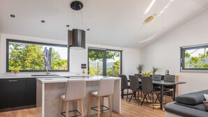 Eine moderne Küche mit Kochinsel, Essbereich mit Stühlen und einer Couch.
