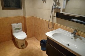 A bathroom with a toilet, sink, and shower. - Jinchuan Noah Ark Hotel (Jinchuan)