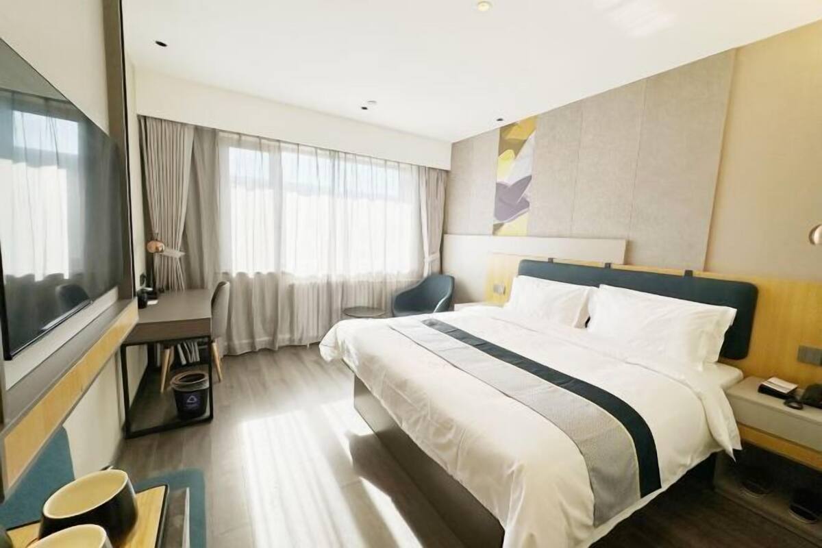 Une chambre d’hôtel avec un lit, une télévision, un bureau et une chaise.