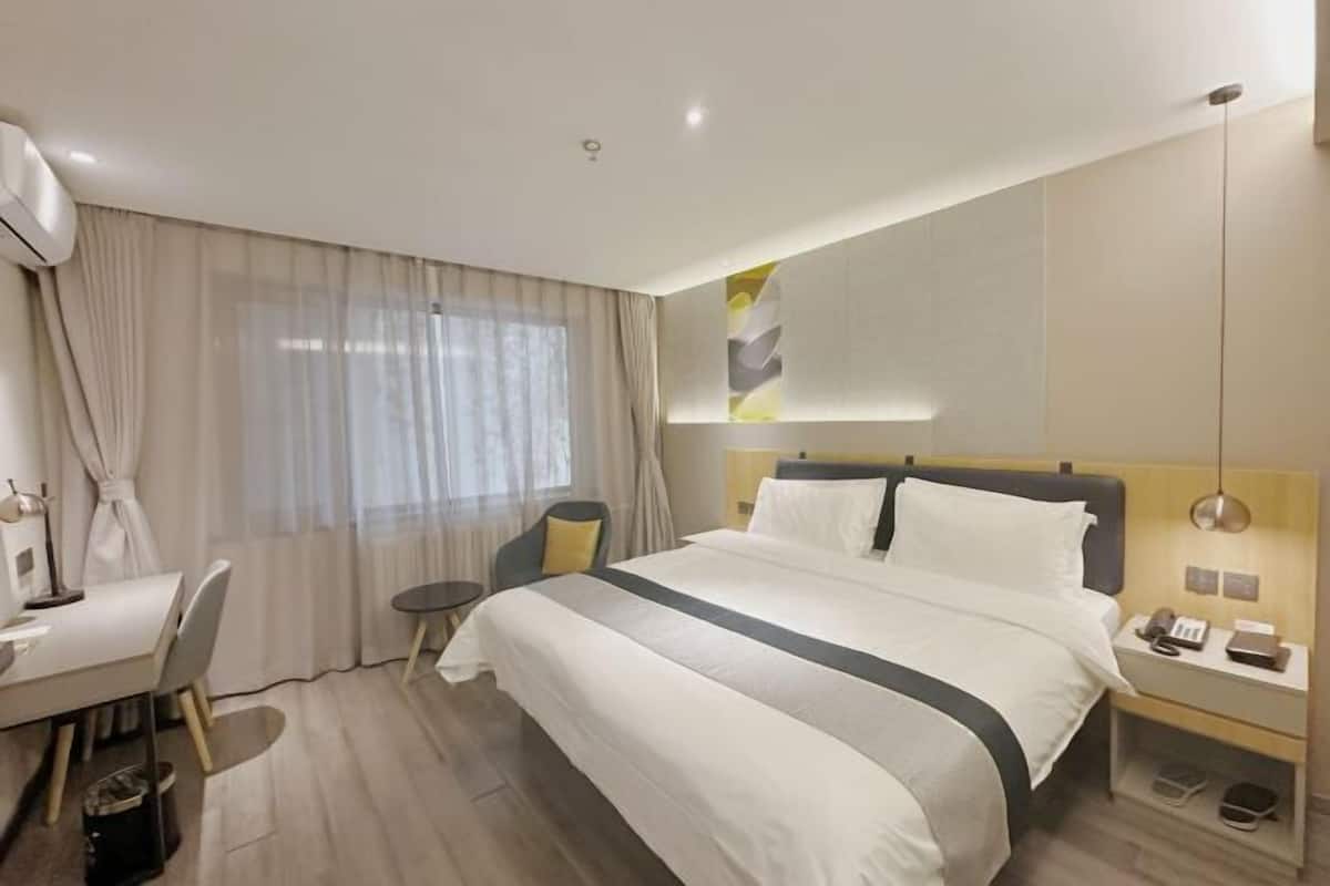 Une chambre d’hôtel moderne, dotée d’un grand lit, d’un bureau et d’une chaise.