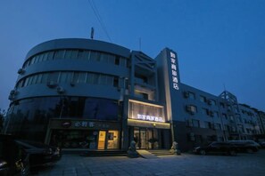 A multi-story hotel with a curved facade, a visible entrance, and a sign indicating a restaurant or dining area.