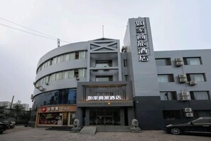 A hotel with a modern design, featuring a prominent vertical sign and a curved facade.