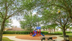 Un parque infantil con un tobogán, una mesa de picnic y árboles alrededor.