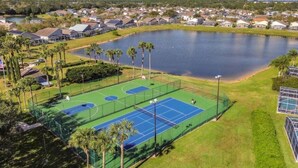 Vista aérea de una zona residencial con cancha de tenis, un lago y casas.