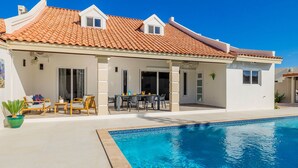 Ein Haus mit Schwimmbad, einer überdachten Terrasse und einem Ziegeldach.