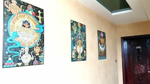 A hallway with three framed artworks on the wall, a dark wooden door, and a ceiling light. - Shangri-la Xiangruiju Inn (Shangri-La)