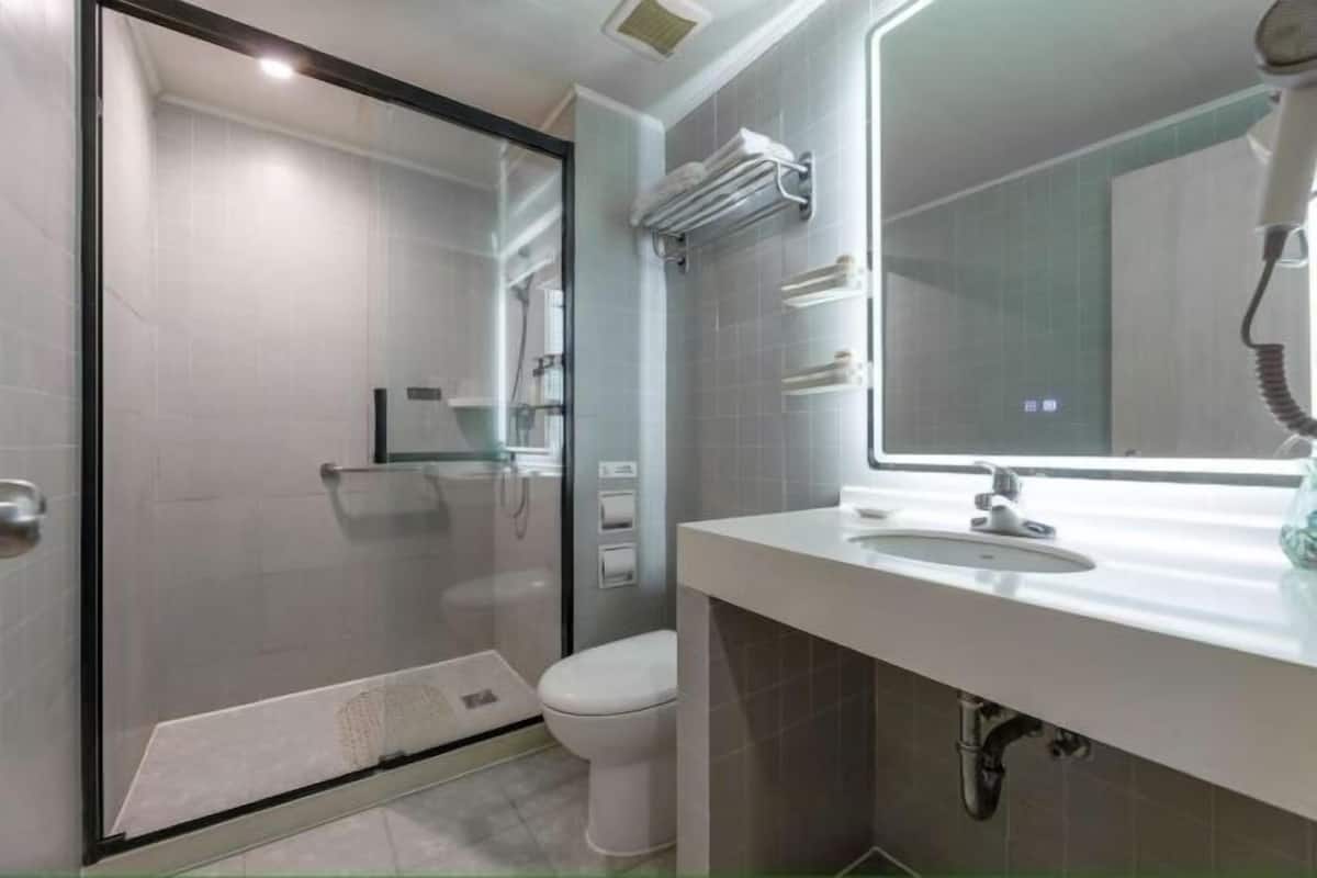 A modern bathroom with a glass shower enclosure, a toilet, a sink with a mirror, and a towel rack.