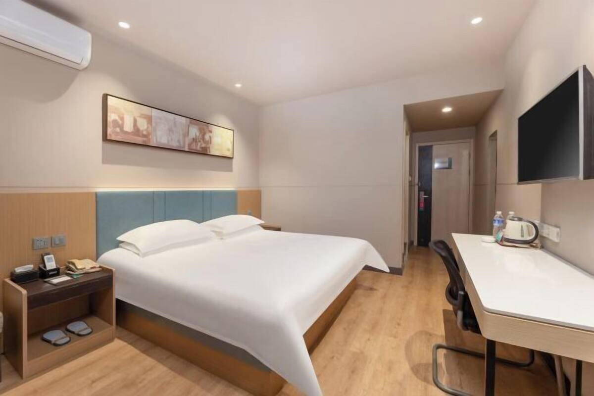 Ein Hotelzimmer mit Bett, Nachttisch, Stuhl, Schreibtisch und einem Bild an der Wand.