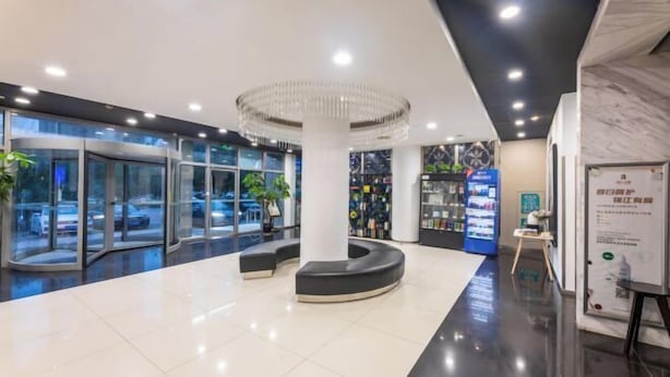 Eine moderne Lobby mit einer zentralen Säule, Glastüren und einem Automaten.