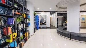 Eine moderne Lobby mit einer gebogenen Sitzgruppe, einer zentralen Kunstausstellung und einer Auswahl an Büchern sowie dekorativen Gegenständen auf Regalen.