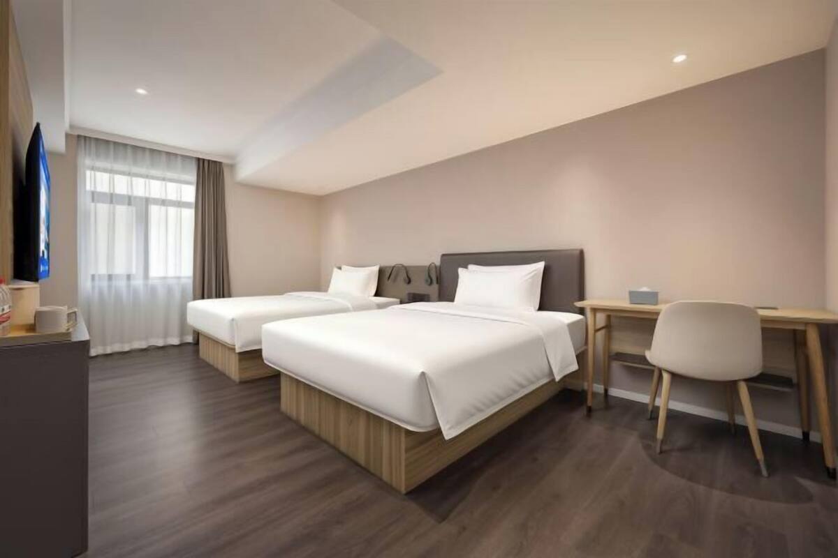 A hotel room with two beds, a desk, and a chair.