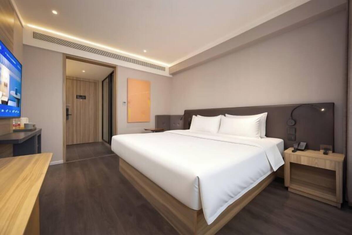 A modern hotel room with a large bed, bedside tables, a desk, and a television.