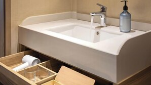 Un bagno con un lavandino bianco, una boccetta di sapone e un porta asciugamani.