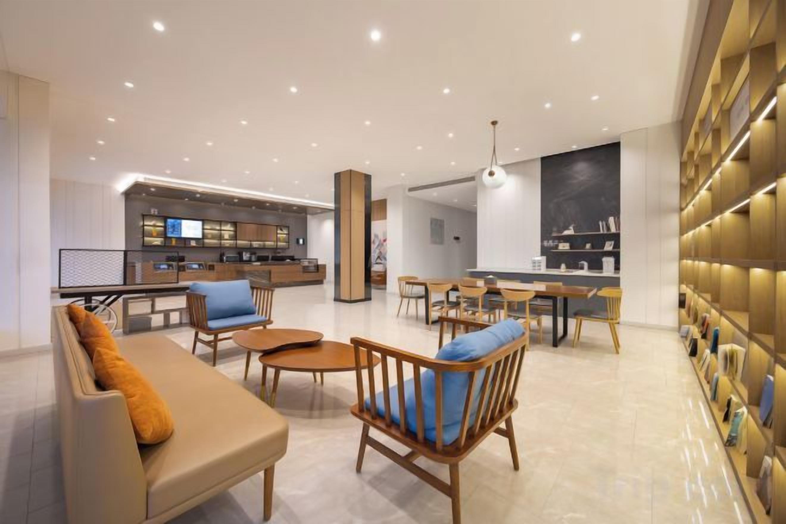 A modern hotel lobby with a bar area, seating arrangements, and a bookshelf.