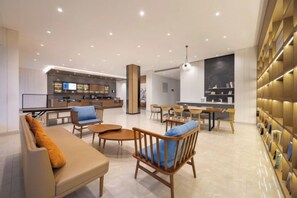 A modern hotel lobby with a bar area, seating arrangements, and a bookshelf. - HanTing Hotel (Shenyang Zhongjie Huaiyuanmen Subway Station) (Shenyang)