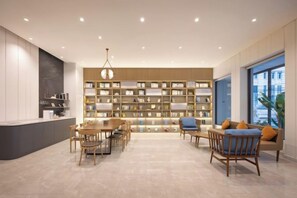 A modern interior with a dining area, bookshelves, and a large window. - HanTing Hotel (Shenyang Zhongjie Huaiyuanmen Subway Station) (Shenyang)