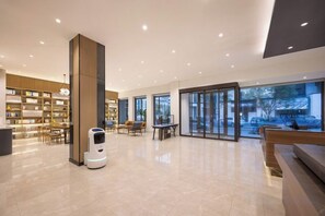 A spacious lobby with a robot, seating areas, and a large bookshelf. - HanTing Hotel (Shenyang Zhongjie Huaiyuanmen Subway Station) (Shenyang)