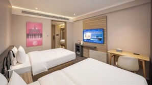 Una camera d'albergo con due letti, una scrivania, una televisione e un quadro appeso al muro.