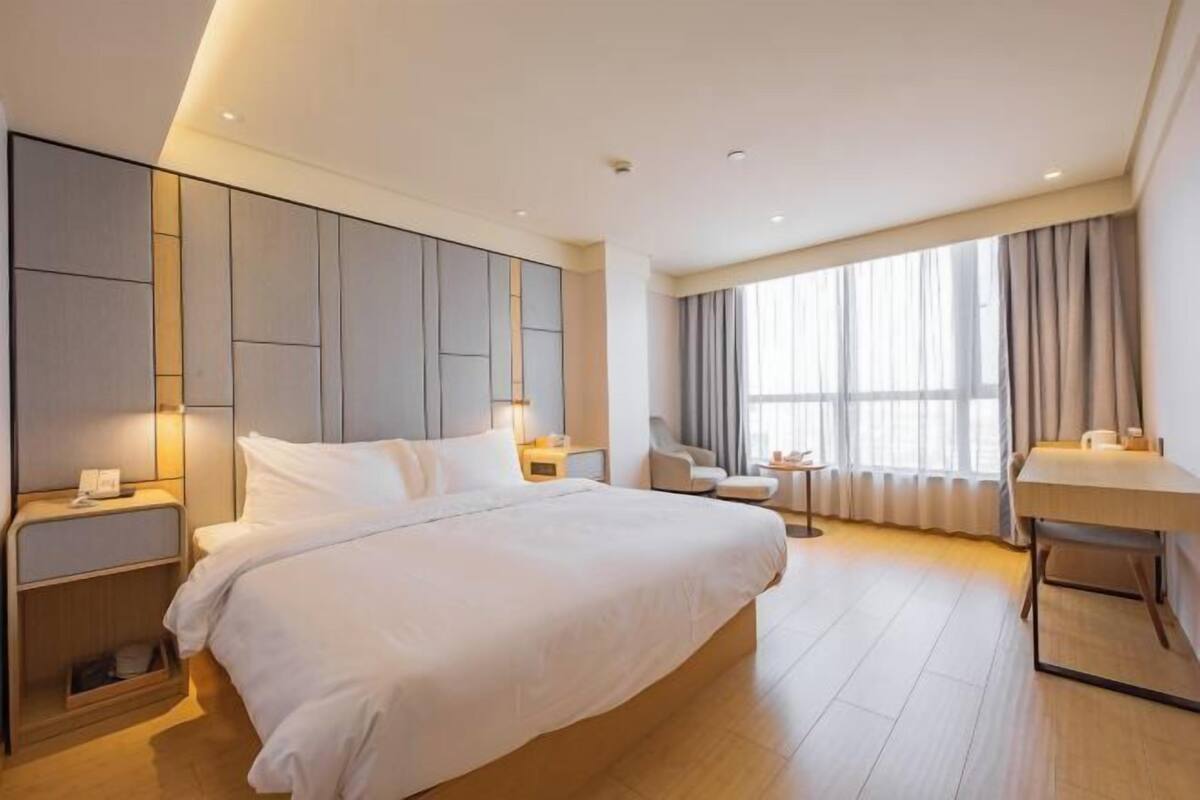 Una habitación de hotel moderna con una cama grande, mesitas de noche, un escritorio y una zona de estar.