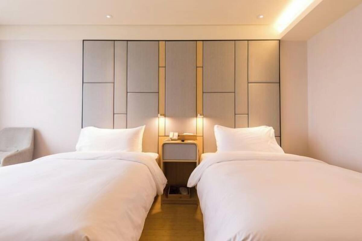 Una habitación de hotel con dos camas, una mesita de noche con lámpara y una silla.