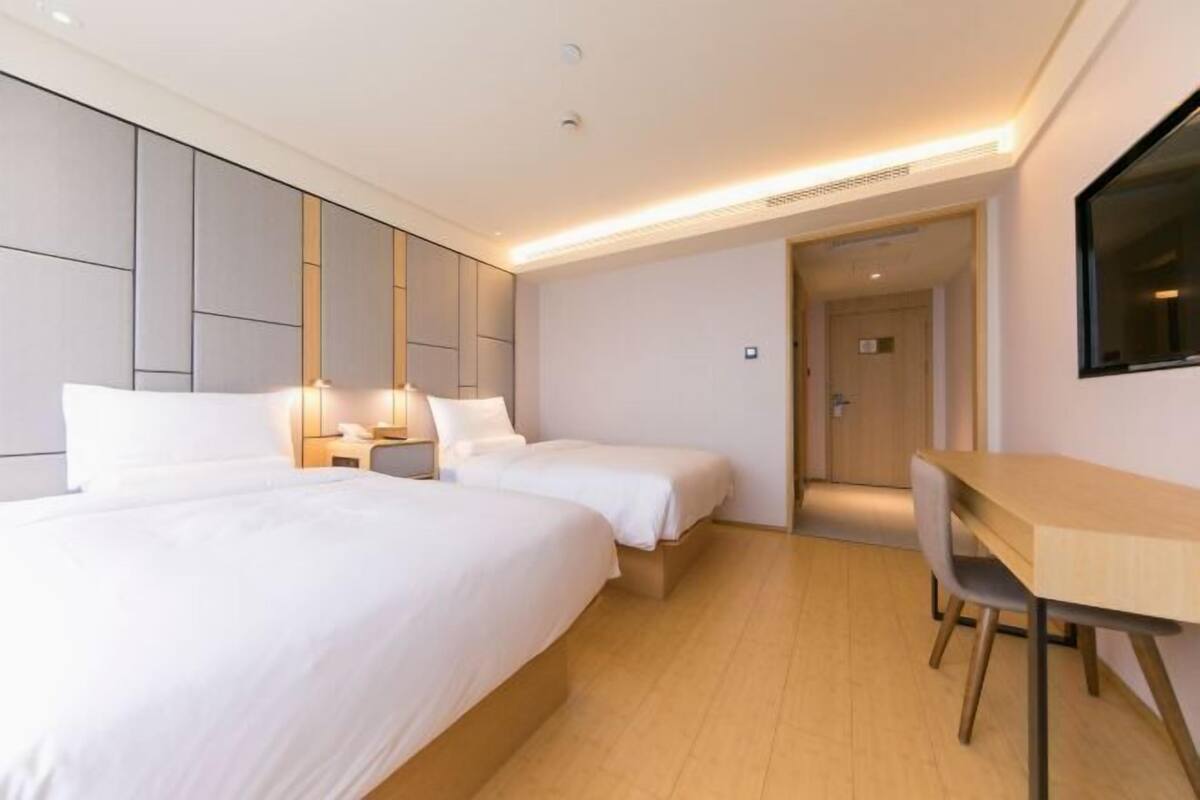 Habitación de hotel con dos camas, un escritorio y una silla.