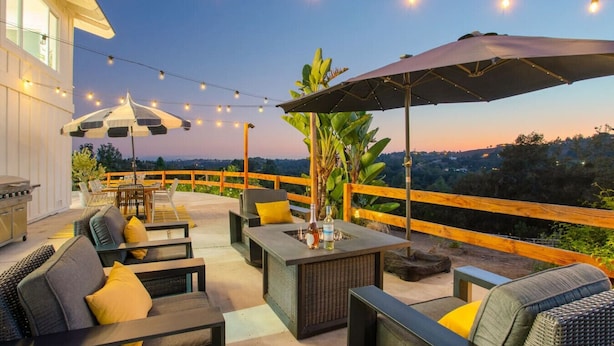 Un patio al aire libre con asientos, luces colgantes y vistas del paisaje.